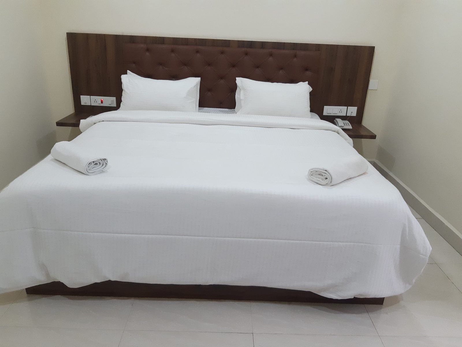 King bed made up with fresh white linen in a Deluxe A/C room
